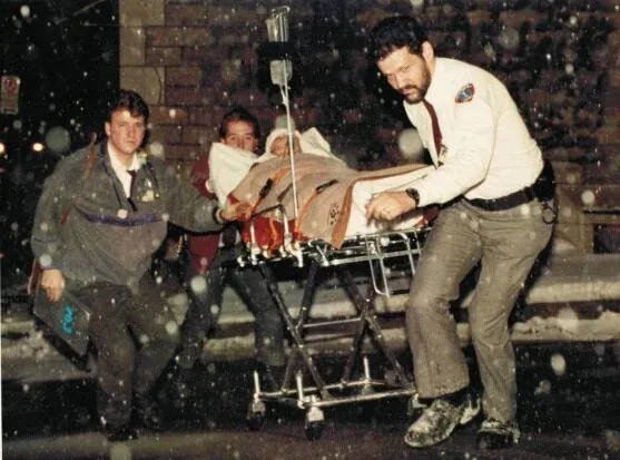 Emergency responders carrying a wounded woman on a stretcher through falling snow in Montreal, December 6, 1989